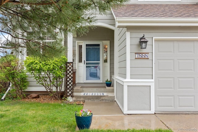 entrance to property featuring a shingled roof and a garage