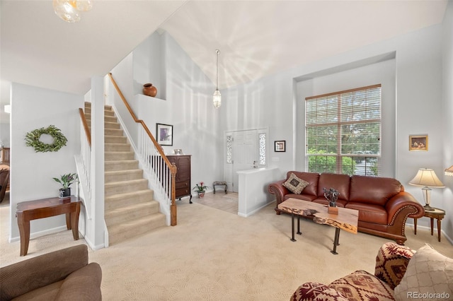 living area featuring carpet flooring, stairway, baseboards, and a high ceiling