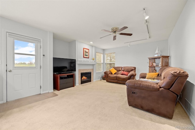 living room with track lighting, carpet floors, a ceiling fan, and a fireplace