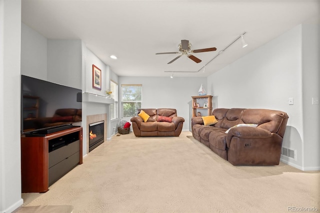carpeted living room with rail lighting, ceiling fan, baseboards, and a tile fireplace