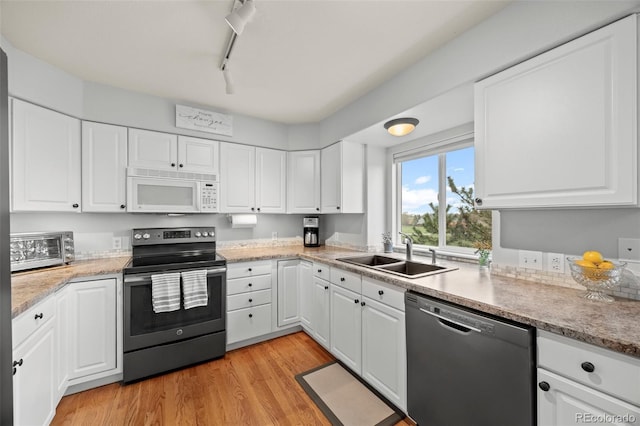 kitchen with stainless steel appliances, a sink, white cabinets, light wood-type flooring, and track lighting