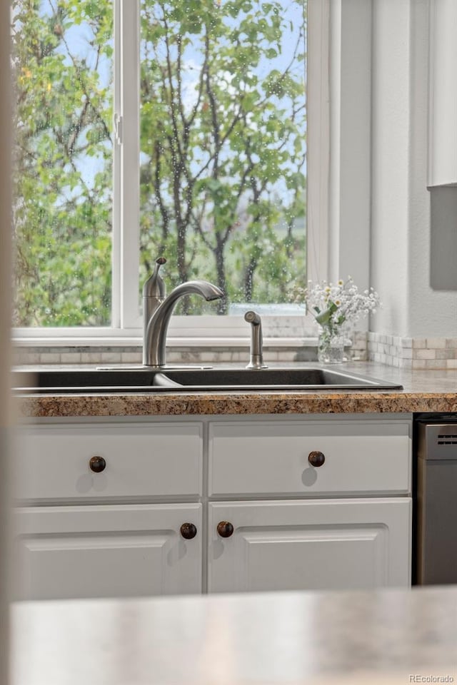 kitchen view of white cabinetry, dishwasher, and bar with sink