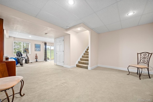 sitting room featuring carpet, stairs, baseboards, recessed lighting, and a drop ceiling