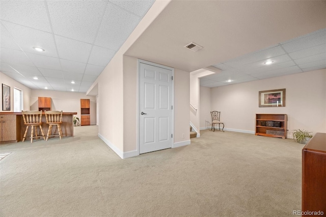 sitting room featuring carpet flooring, a paneled ceiling, stairs, a dry bar, and baseboards