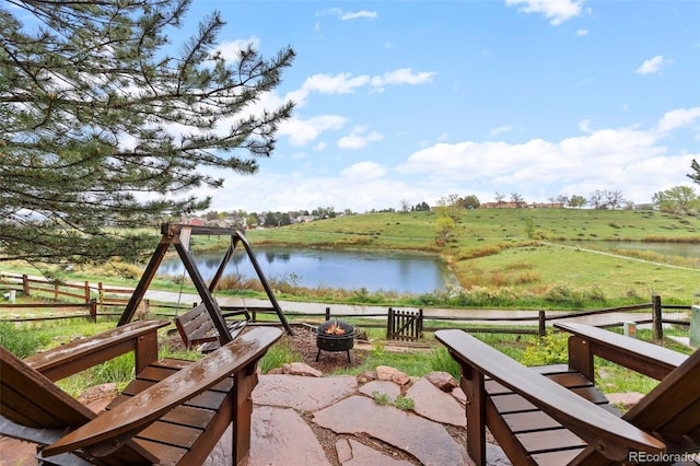 view of patio with an outdoor fire pit, a water view, and fence