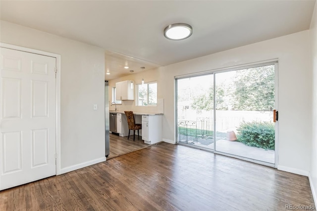 unfurnished living room with a sink, baseboards, and wood finished floors