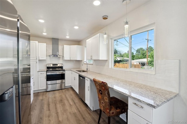 kitchen with decorative backsplash, wall chimney range hood, white cabinets, a sink, and stainless steel appliances