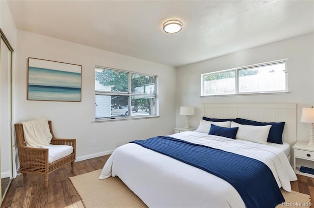 bedroom featuring baseboards, multiple windows, and wood finished floors