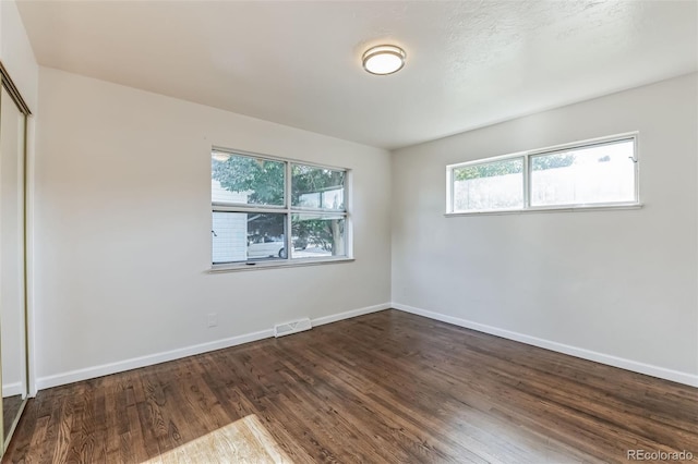 unfurnished bedroom featuring multiple windows, a closet, wood finished floors, and visible vents