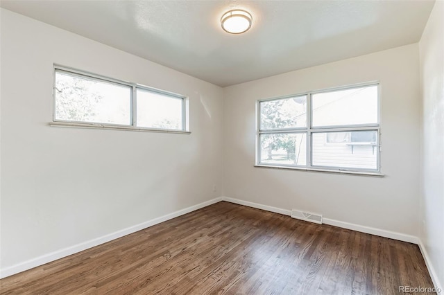 empty room featuring visible vents, baseboards, and wood finished floors
