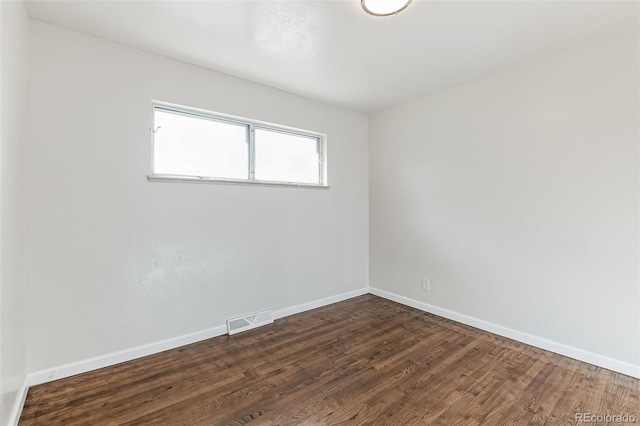 unfurnished room with baseboards, dark wood-style flooring, and visible vents