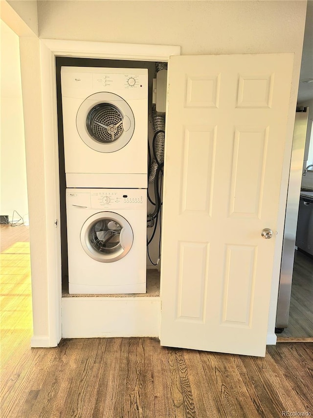 washroom featuring laundry area, stacked washing maching and dryer, and wood finished floors