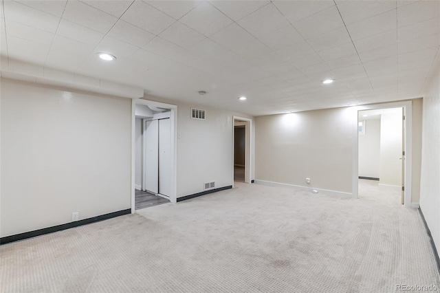 finished below grade area featuring visible vents, recessed lighting, baseboards, and light carpet