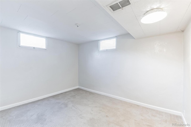 below grade area featuring baseboards, visible vents, plenty of natural light, and carpet