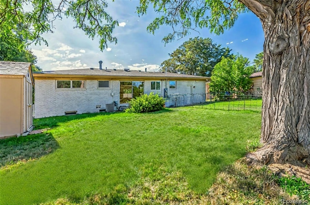 rear view of house with a lawn, brick siding, fence, and central air condition unit