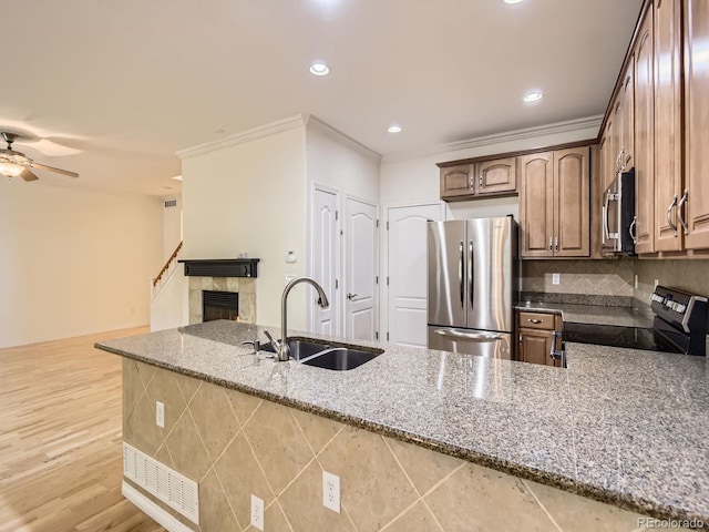 11883 E Fair Ave, Greenwood Village, CO 80111 - kitchen featuring appliances with stainless steel finishes, stone countertops, a tile fireplace, open floor plan, and ceiling fan