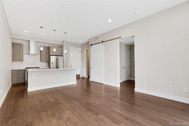 unfurnished living room featuring a barn door and dark wood-type flooring