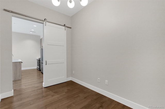 spare room with a barn door and wood-type flooring