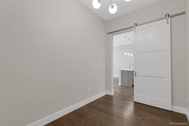 spare room featuring dark hardwood / wood-style floors and a barn door