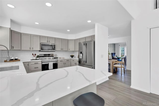 275 S Pembrook St, Castle Rock, CO 80104 - kitchen featuring stainless steel appliances, gray cabinets, a sink, light stone counters, and backsplash