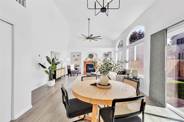 275 S Pembrook St, Castle Rock, CO 80104 - dining space featuring high vaulted ceiling, built in shelves, a chandelier, light wood-type flooring, and a brick fireplace