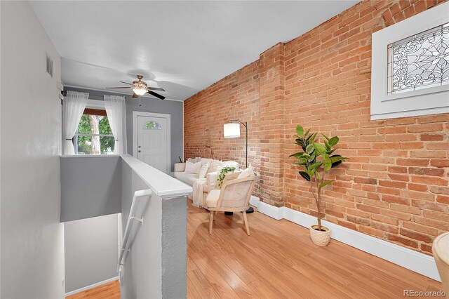 1005 S Pennsylvania St, Denver, CO 80209 - living area featuring brick wall, light wood-style floors, a ceiling fan, and an upstairs landing