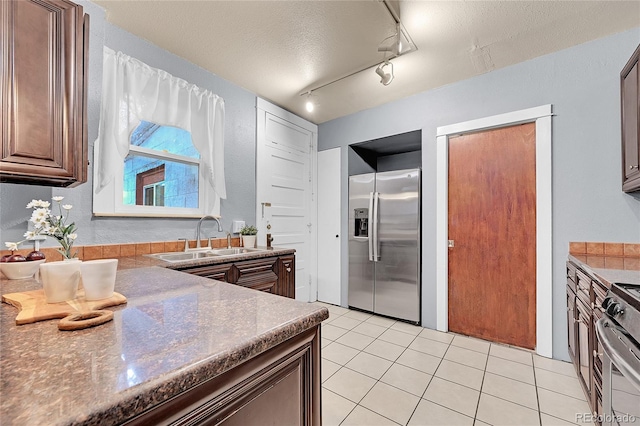 1005 S Pennsylvania St, Denver, CO 80209 - kitchen with appliances with stainless steel finishes, light tile patterned floors, a textured ceiling, dark countertops, and rail lighting
