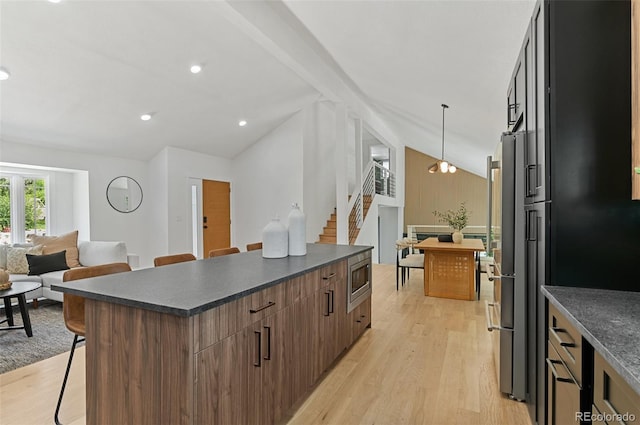 4269 Carter Trl, Boulder, CO 80301 - kitchen with dark countertops, a kitchen bar, light wood-style floors, stainless steel microwave, and a center island