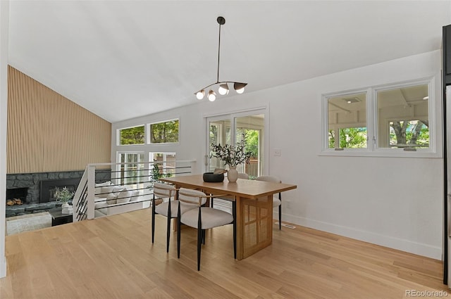 4269 Carter Trl, Boulder, CO 80301 - dining space with baseboards, lofted ceiling, light wood-type flooring, a stone fireplace, and a chandelier