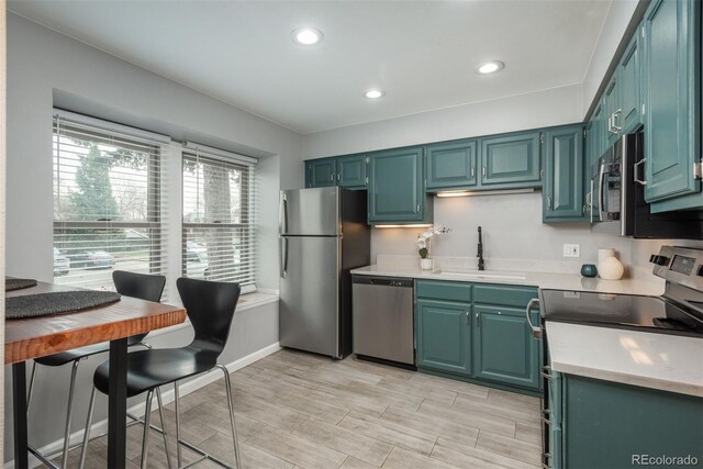 kitchen with recessed lighting, light countertops, wood tiled floor, stainless steel appliances, and a sink
