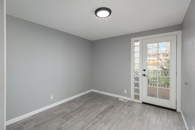 unfurnished room featuring plenty of natural light, visible vents, baseboards, and wood finished floors