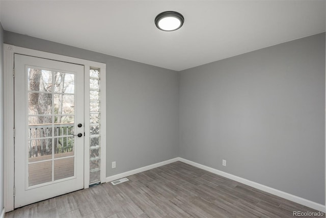 spare room with wood finished floors, baseboards, and visible vents