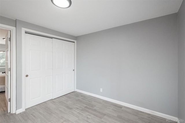 unfurnished bedroom with a closet, light wood-style floors, and baseboards
