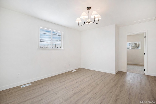 unfurnished room with a notable chandelier and light wood-type flooring