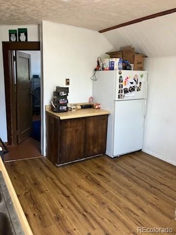 440 Colorado Ave, Stratton, CO 80836 - kitchen with freestanding refrigerator, dark wood-type flooring, light countertops, dark brown cabinets, and vaulted ceiling