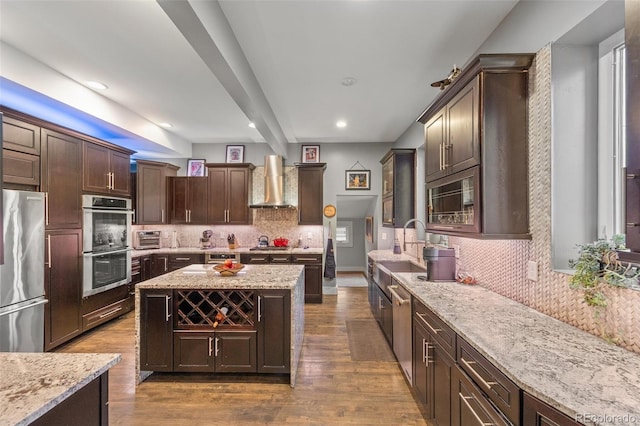3410 Pecos St, Denver, CO 80211 - kitchen featuring appliances with stainless steel finishes, wall chimney range hood, decorative backsplash, wood finished floors, and dark brown cabinetry