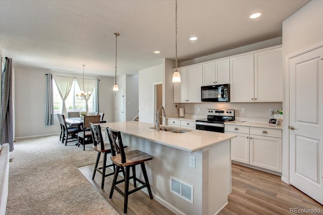 4505 Cholla Trl, Castle Rock, CO 80104 - kitchen featuring black microwave, stainless steel range with electric stovetop, a kitchen island with sink, white cabinetry, and recessed lighting