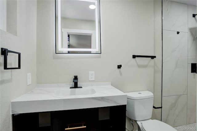 bathroom with a stall shower, toilet, vanity, and a textured wall