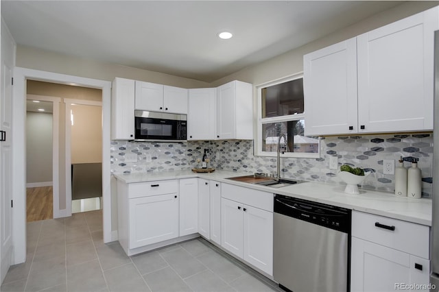 kitchen featuring backsplash, light tile patterned floors, white cabinets, stainless steel appliances, and a sink