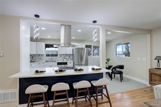 kitchen with a kitchen breakfast bar, island exhaust hood, visible vents, and freestanding refrigerator