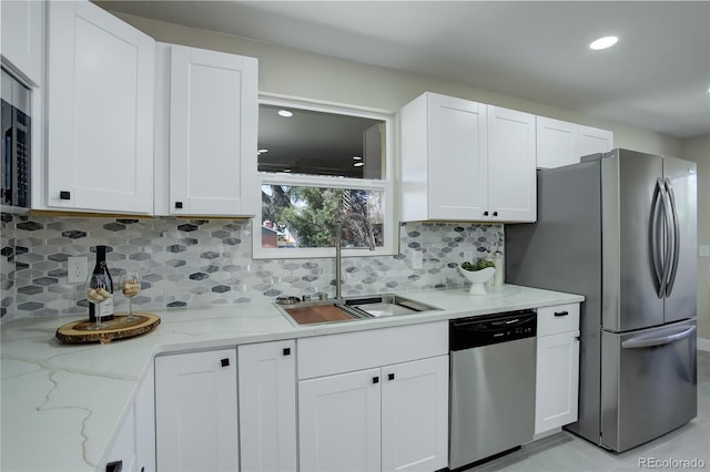 kitchen featuring a sink, backsplash, appliances with stainless steel finishes, and white cabinetry