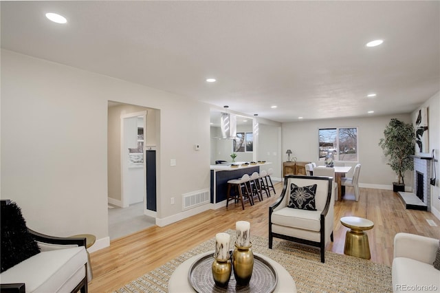 living area with light wood-style flooring, recessed lighting, visible vents, and baseboards