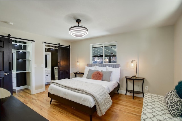 bedroom featuring a barn door, wood finished floors, and baseboards