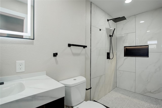 full bathroom featuring vanity, toilet, a textured wall, and a marble finish shower