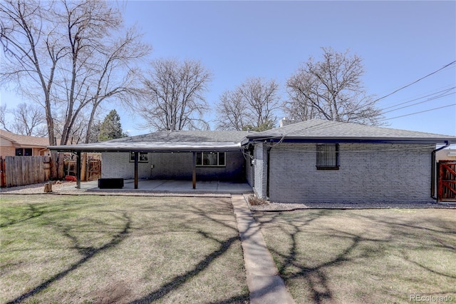 back of property with a patio area, a lawn, brick siding, and fence