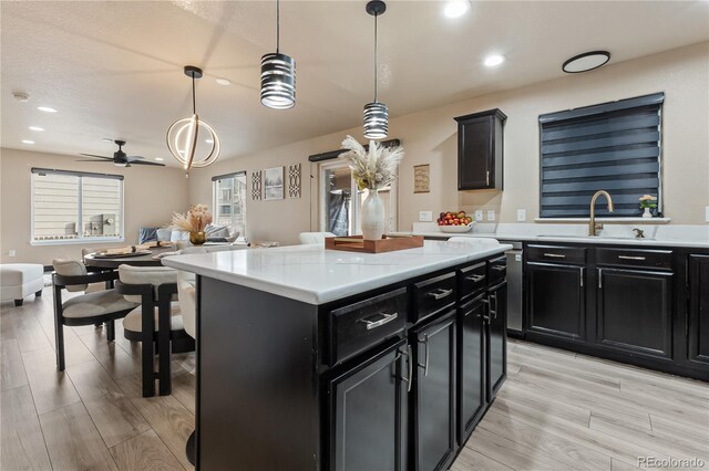 kitchen with a center island, sink, hanging light fixtures, and light hardwood / wood-style flooring