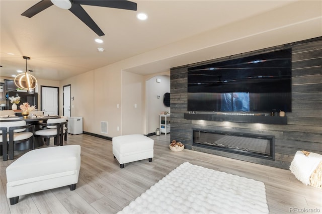 living room featuring hardwood / wood-style flooring, a large fireplace, and ceiling fan