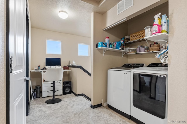 clothes washing area featuring light colored carpet, washing machine and dryer, and a textured ceiling