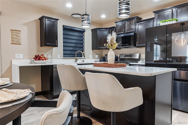 kitchen with hanging light fixtures, stainless steel electric stove, a center island, and a breakfast bar