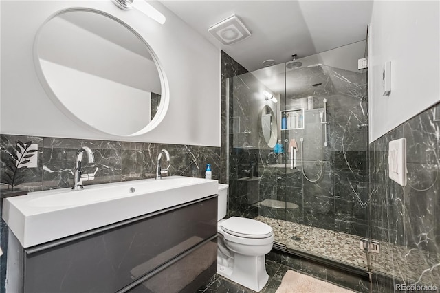 bathroom featuring a shower with door, vanity, tile walls, and toilet